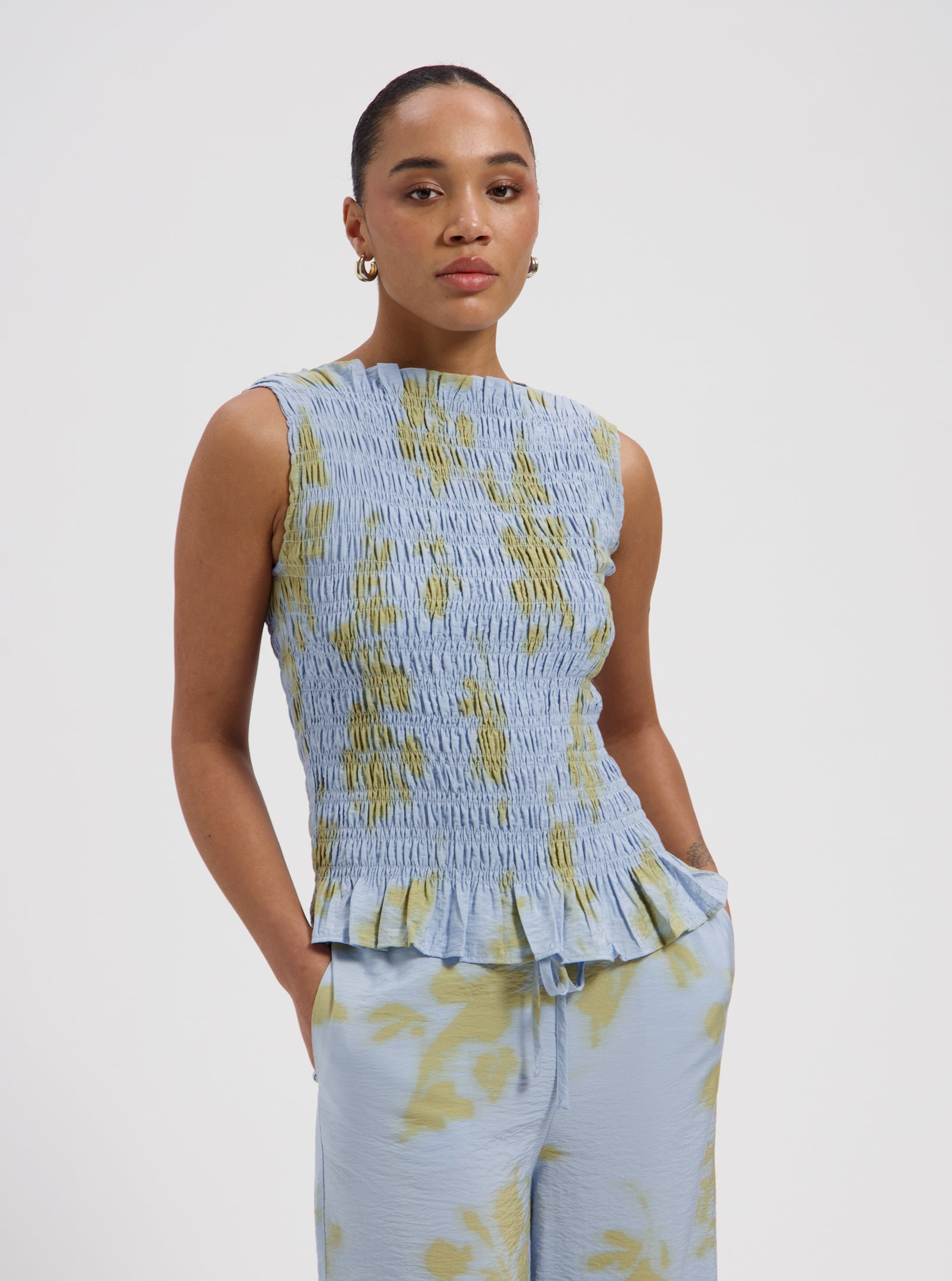 Blue smocked sleeveless top with yellow floral print and ruffle hem by Nous Sommes Labels